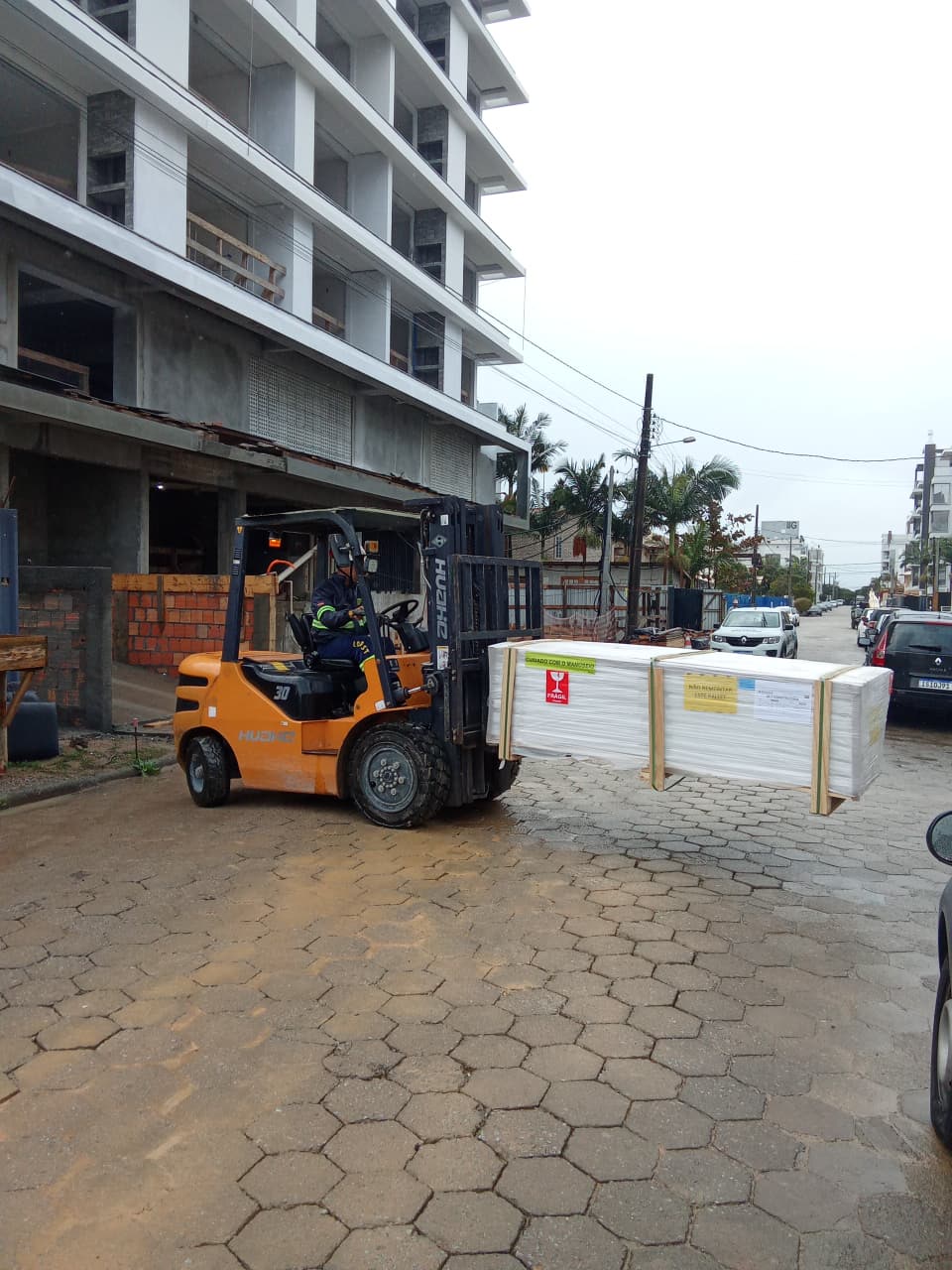 Empilhadeira da Locast levando um palete em frente a um prédio em obra