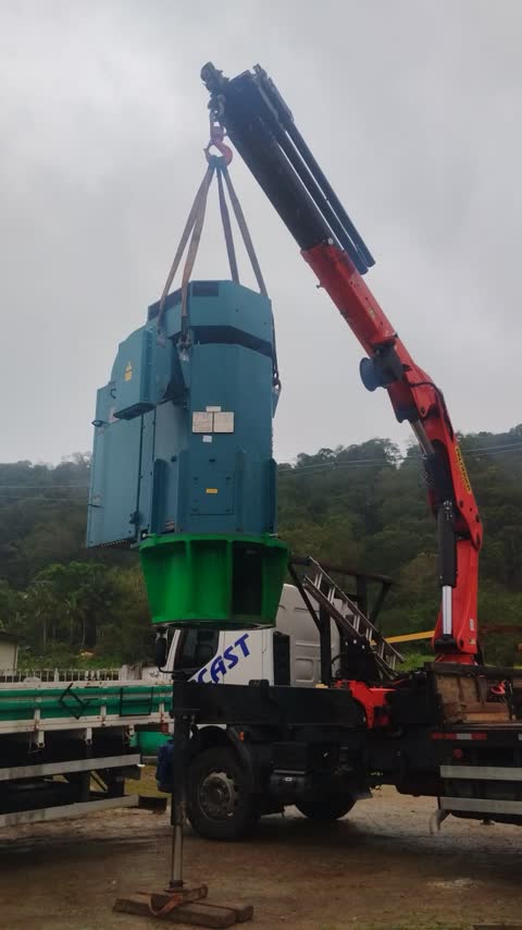 Guindaste articulado içando um motor elétrico industrial de grande porte