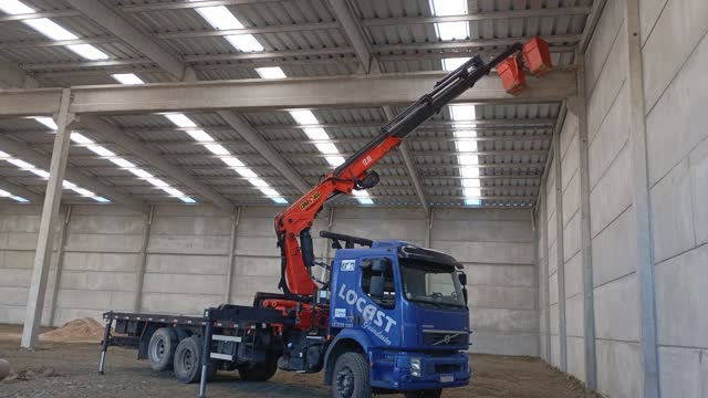 Guindaste articulado trabalhando dentro de um galpão industrial