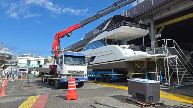 Guindaste articulado içando uma lancha em estaleiro