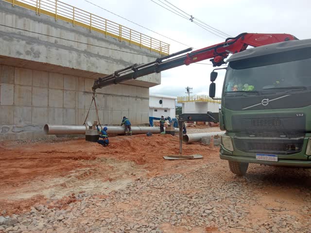 Guindaste articulado posicionando tubos em obra de viaduto