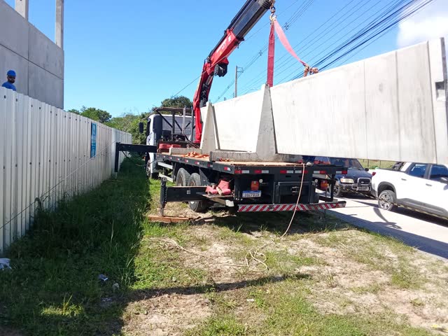 Guindaste articulado içando um muro pré-moldado de concreto