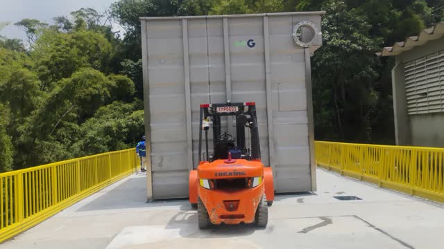 Empilhadeira transportando um equipamento de grande porte sobre passarela