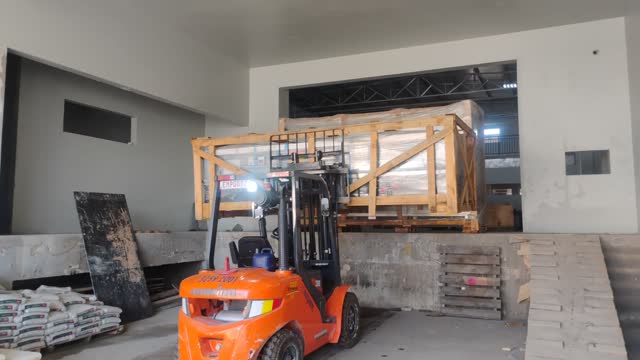 Empilhadeira levando caixa de madeira para dentro de prédio