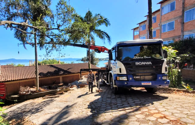 Caminhão com guindaste articulado da Locast trabalhando em rua estreita perto do mar