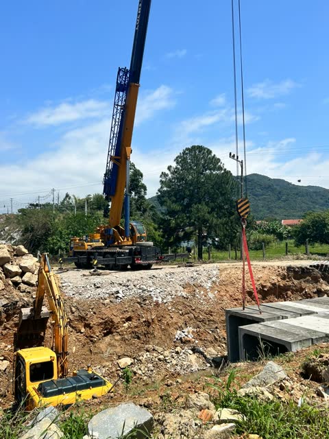 Guindaste telescópico instalando galeria pré-moldada de concreto em obra de drenagem
