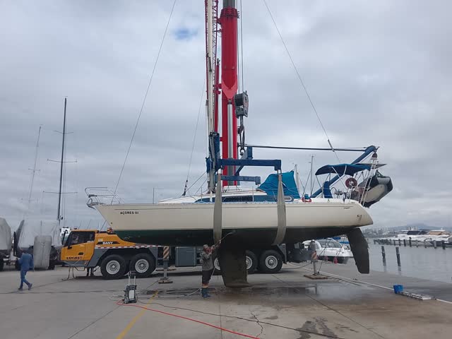 Guindaste telescópico içando um veleiro em marina